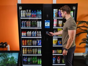 A young man purchases items from a Smart Store in a gym.